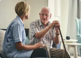 carer sat on sofa with elderly gentleman